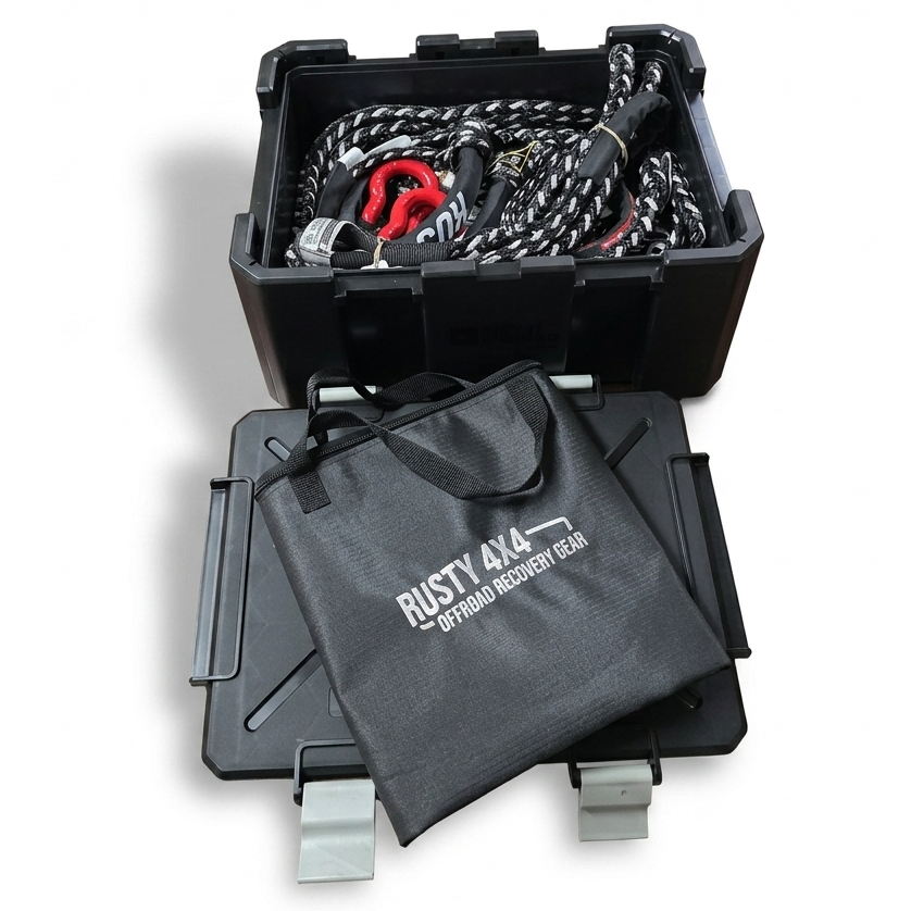 Black ammo crate with recovery gear packed inside, with a lid on the floor next to it and a canvas bag on the lid with white RUSTY 4x4 branding on the bag.